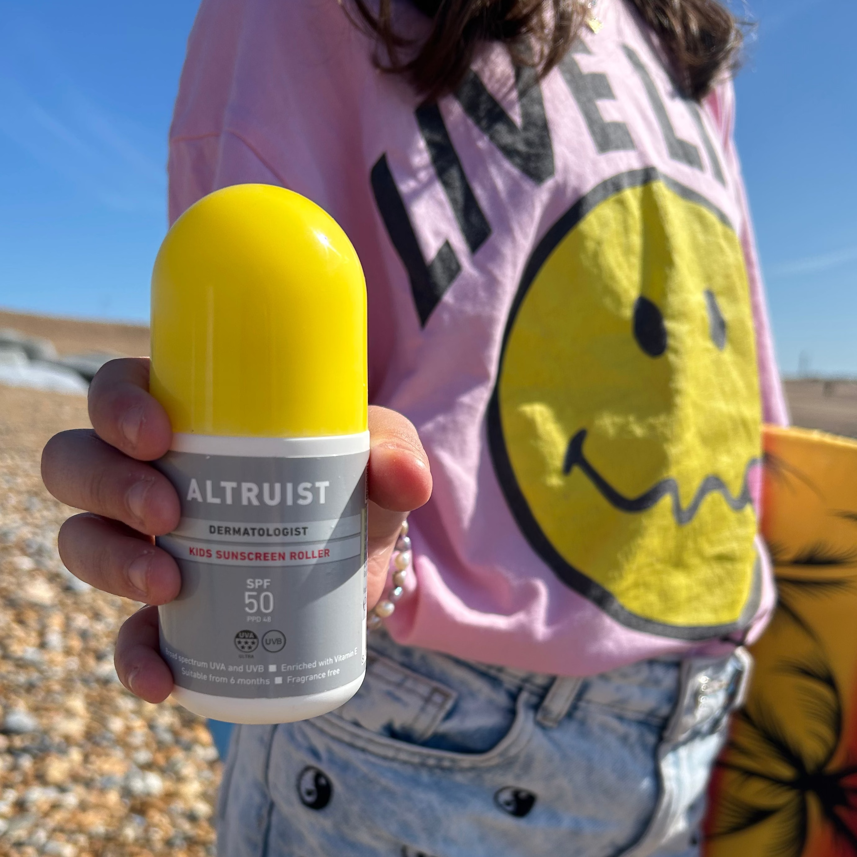 Person holding Altruist Kids Roller sunscreen SPF50 on the beach